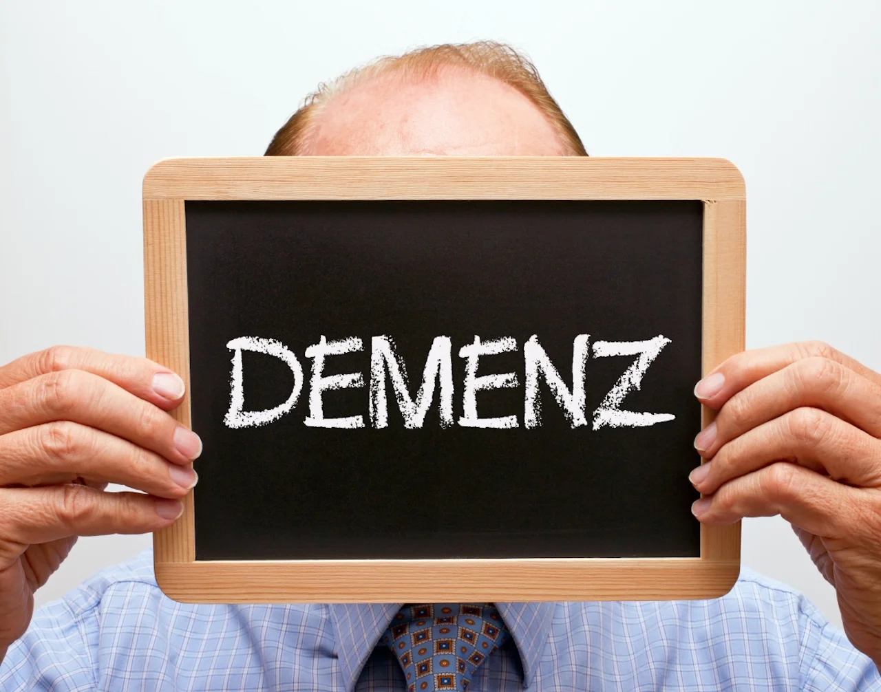 FokusDEMENZ - ein Mann, der die Kreidetafel mit der Aufschrift „DEMENZ“ hält